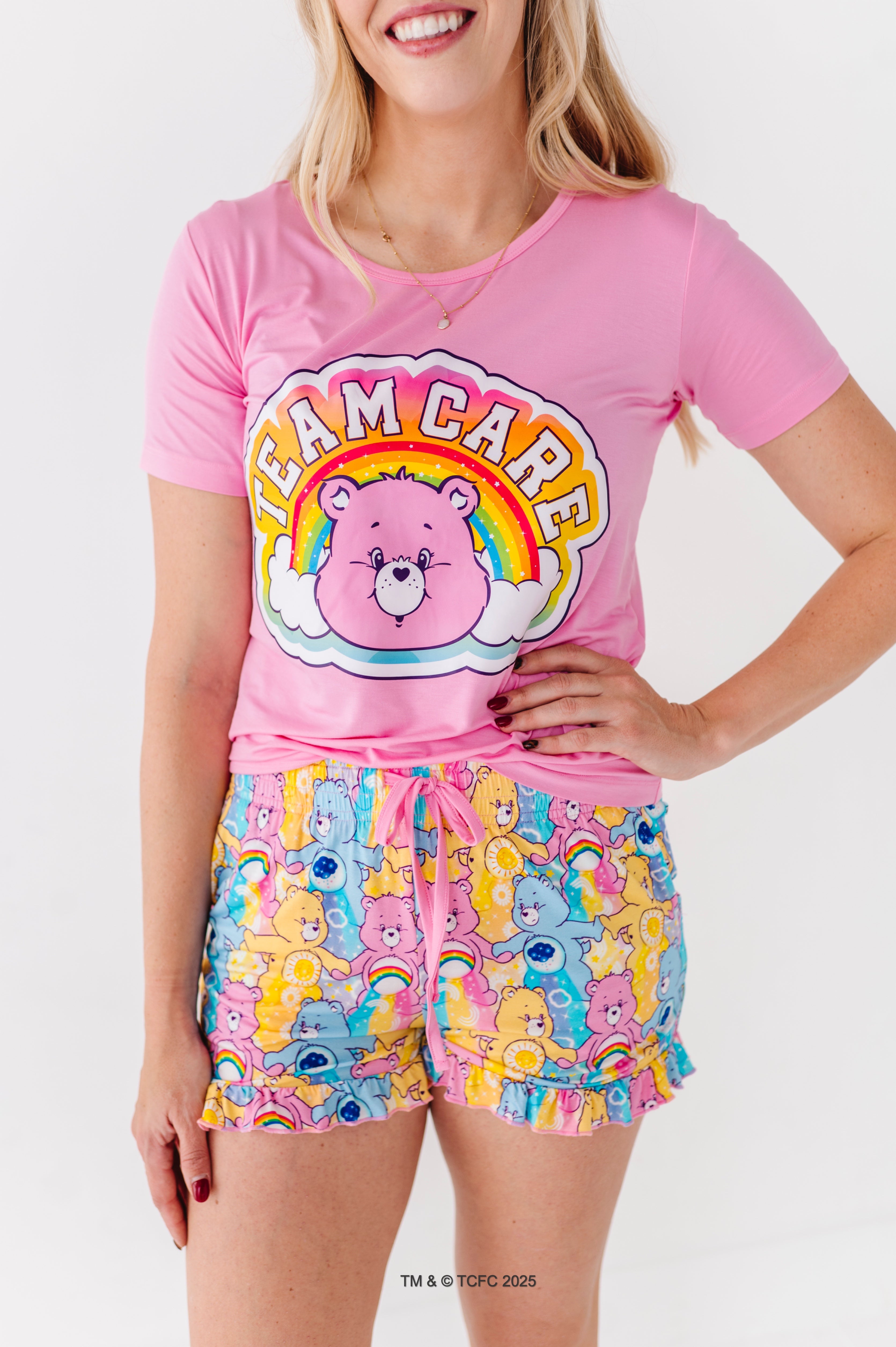 Woman wearing pink Care Bears graphic tee with rainbow bear design and bamboo lounge shorts